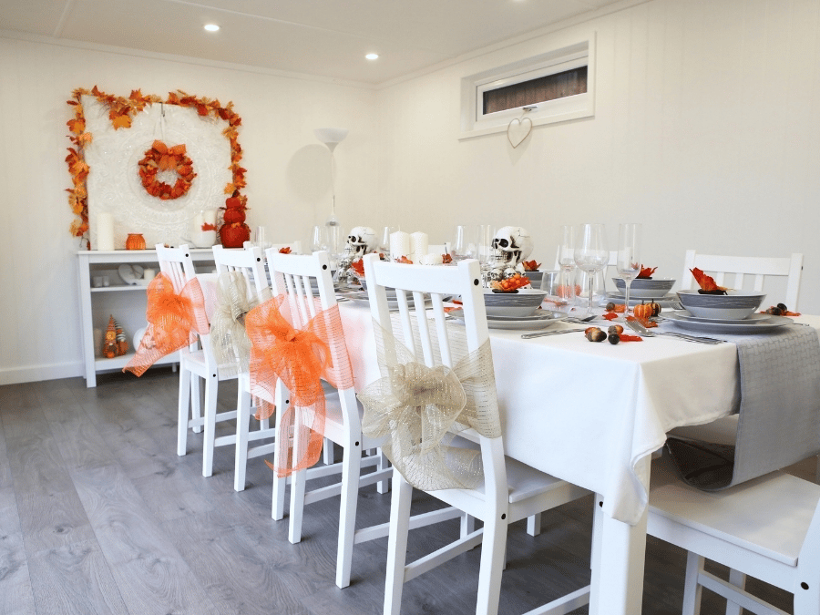 Garden room dining space decorated for Halloween and autumn with pumpkins, skulls and seasonal table decorations.