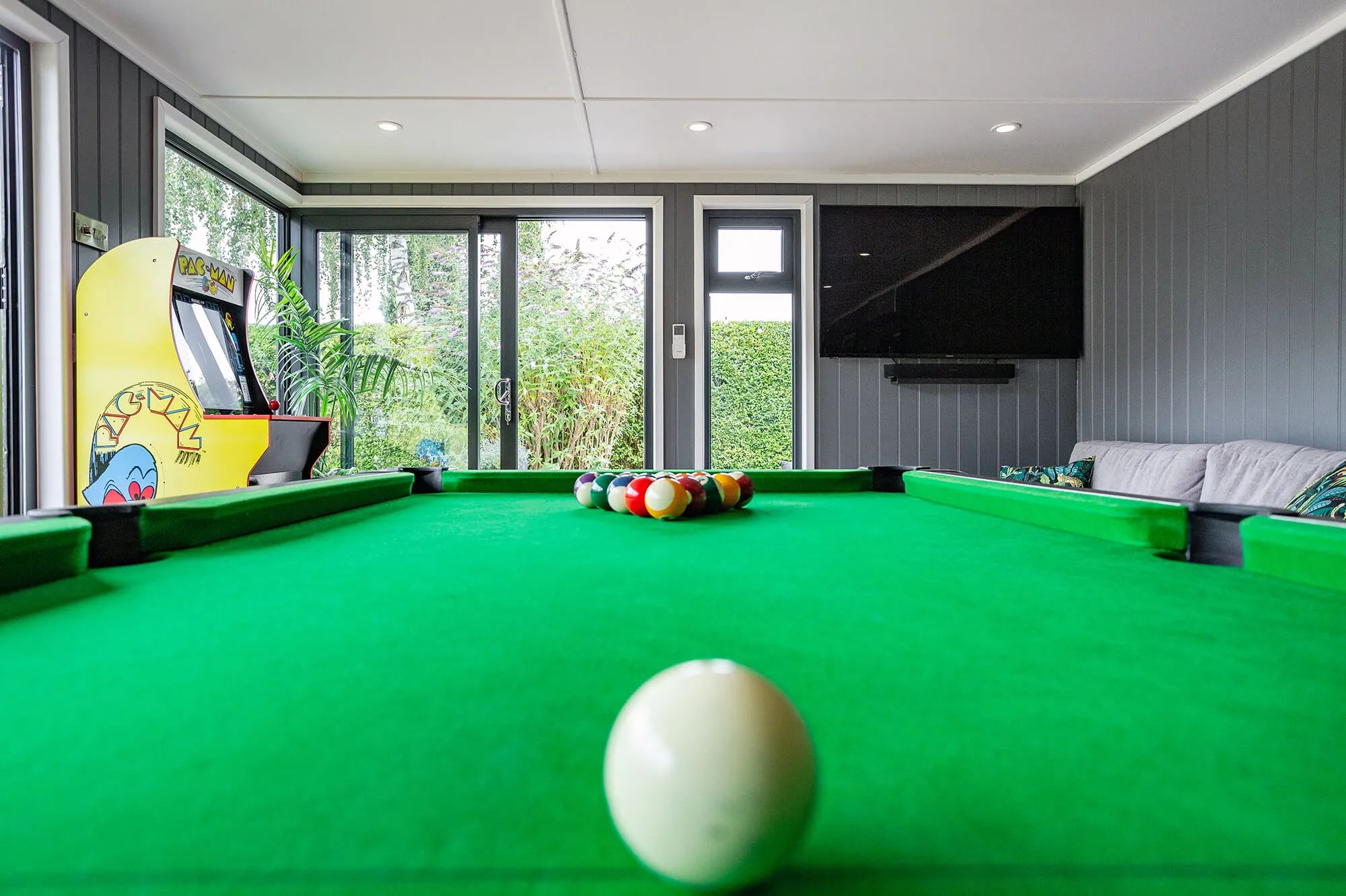 Internal Garden Bar with pool table and bifold doors and pac man machine and flat screen television