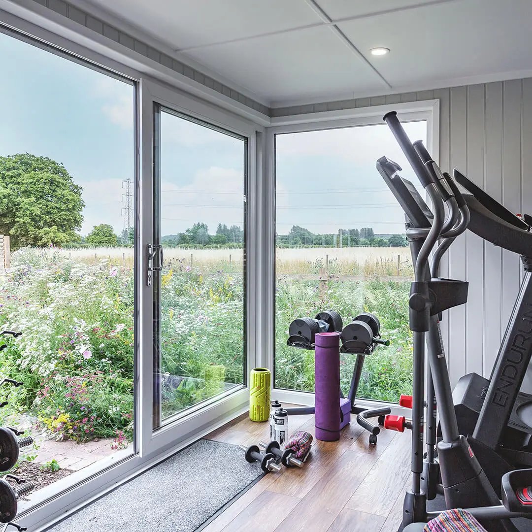 Luxury garden room gym in cedar cladding with garden flowers next to it