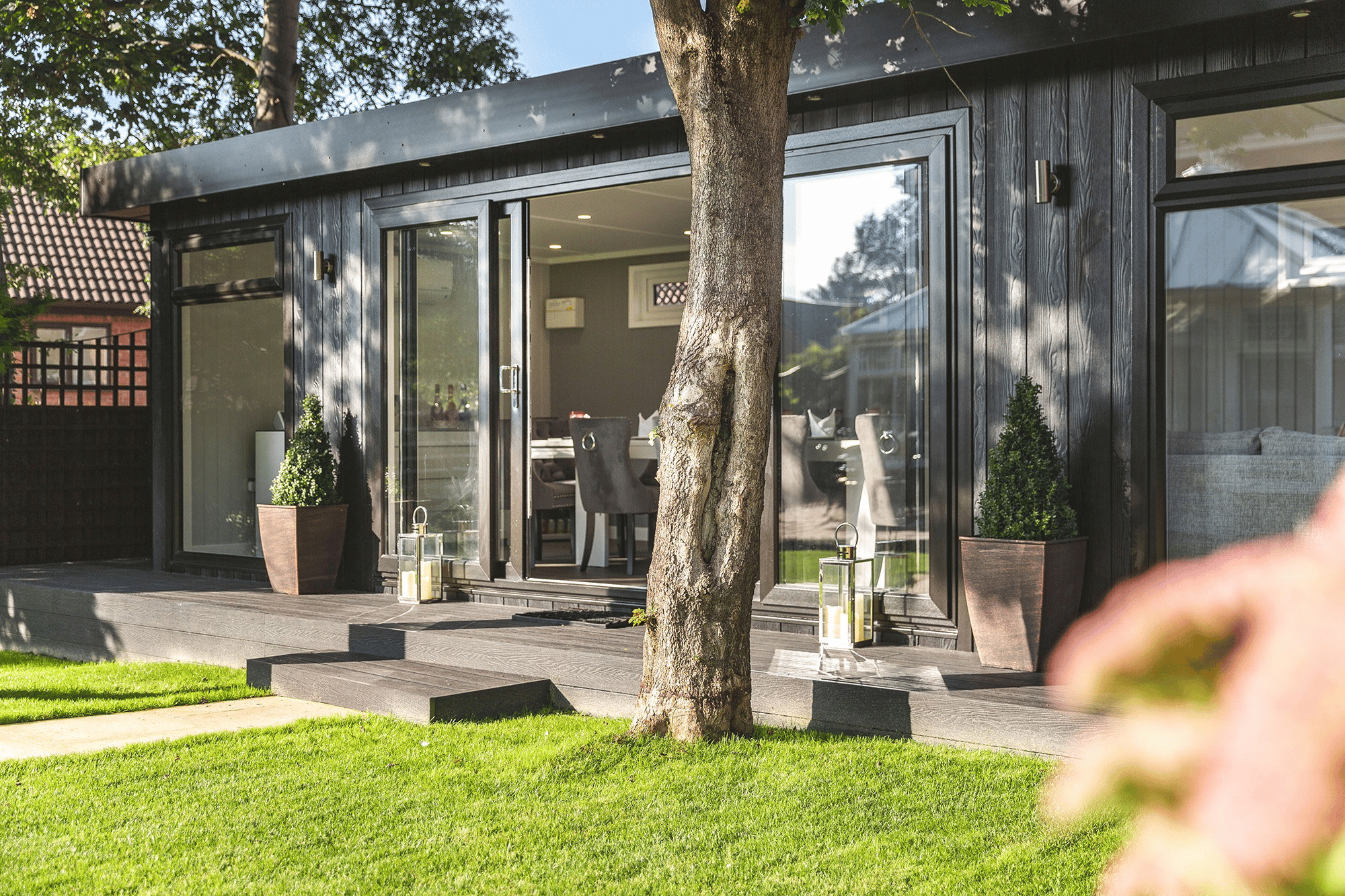 Large Garden Dining Room with Tree in front of it. There is a timber step with potted mini trees either side.