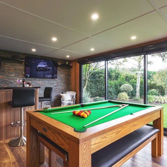 Looking outside from inside of a man cave garden bar, looking across pool table