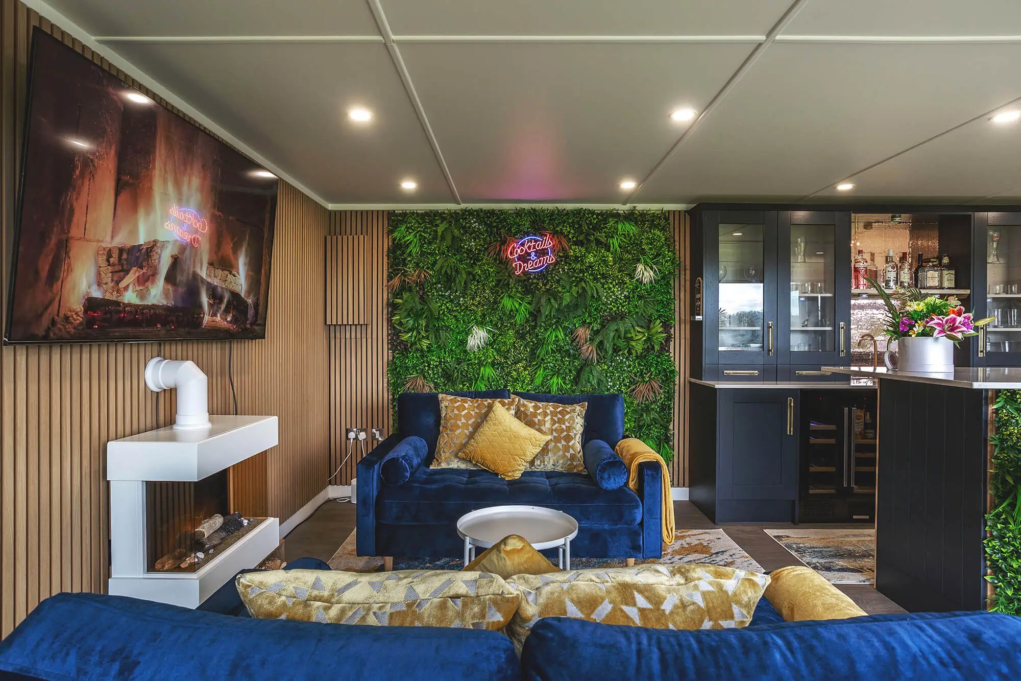 Internal Garden Bar with velvet sofas and plant wall with neon sign and fireplace