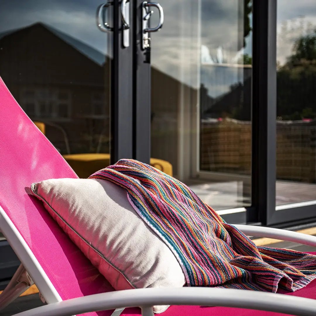 Cabin Master Cedar Garden Room with pink deck chair and colourful towel in front