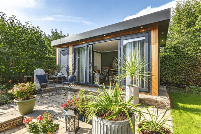 External shot of a cedar garden room snug with black doors and windows and storage cupboard