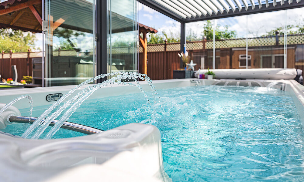 Hydropool swim spa in outdoor location in garden with waterfall feature activated