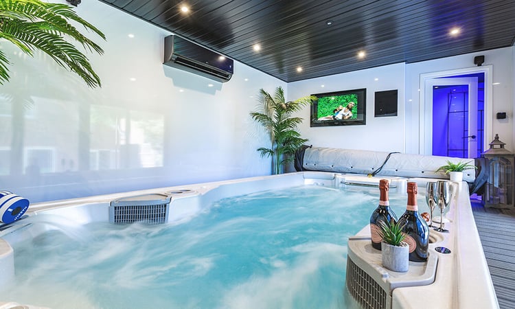 Interior of a garden hot tub room with Hydropool swim spa with bottles of Prosecco and glasses
