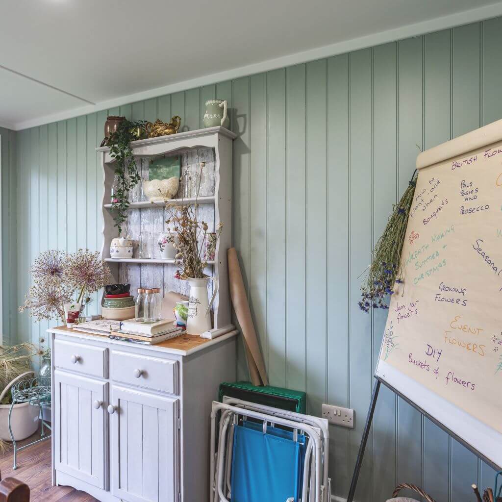 large grey cabinet with whiteboard and notes with vases of flowers inside home business floristry studio 