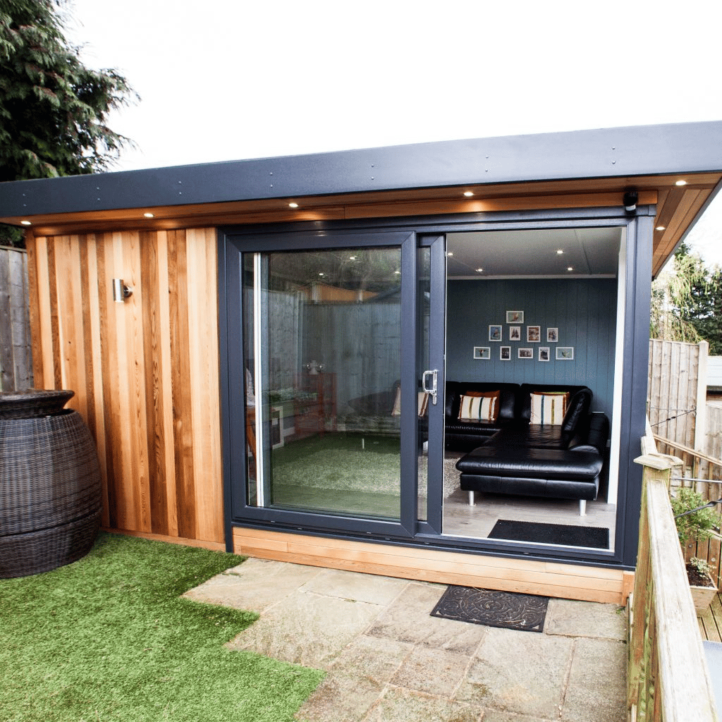 Traditional cedar summerhouse with sliding doors garden building extra room with patio and grassy are and ornamental pot 