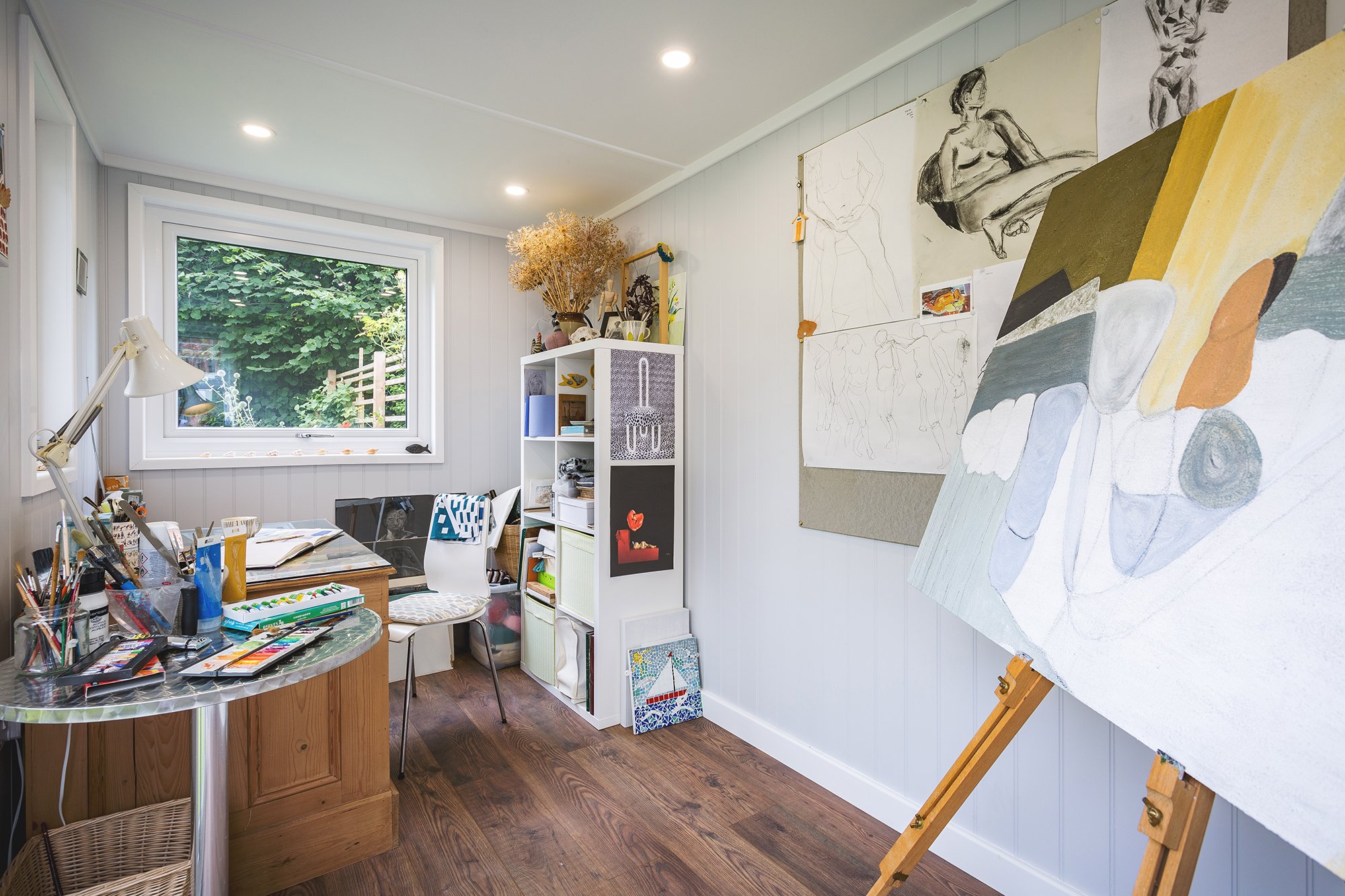 Interior of a garden room artists studio with desk, art materials and easel
