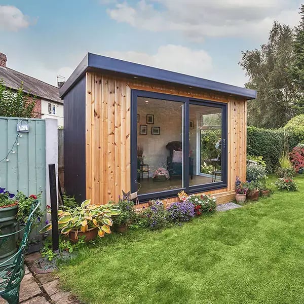 Outside a redwood timber garden cabin with english flowers in garden
