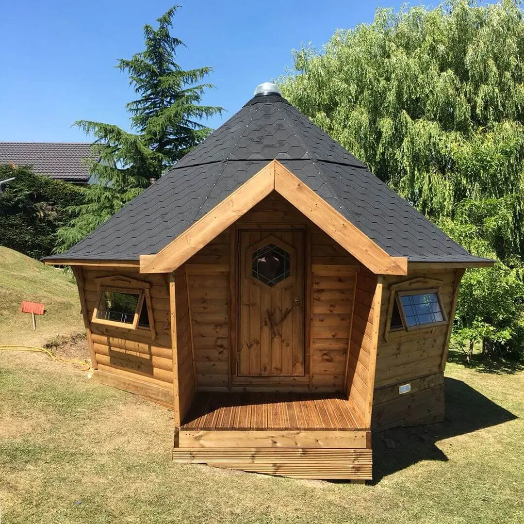 Cabins For Schools black roof building in grassy playground with trees in background and blue sky