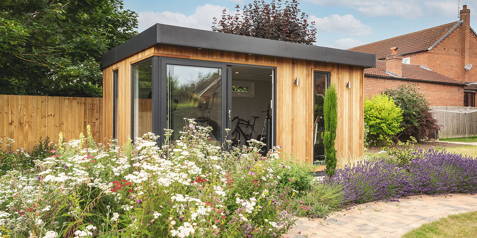Small insulated garden room gym built in cedar in pretty english garden 