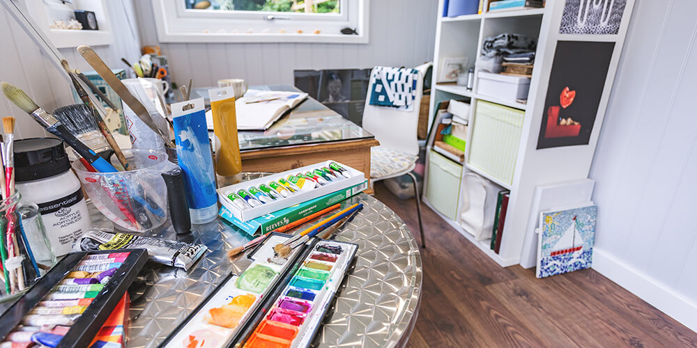 Interior of a garden room artists studio with paints & brushes on desk