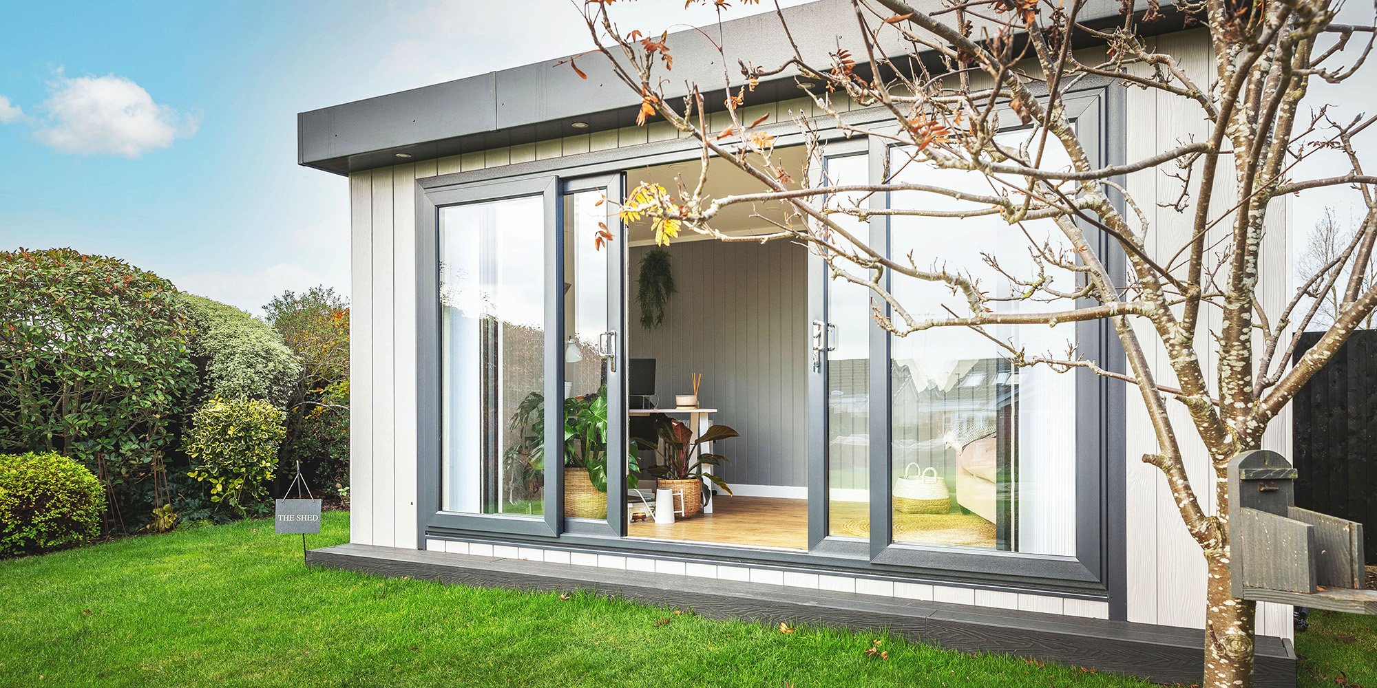 Zero maintenance garden office with black sliding doors open so you can see desk 