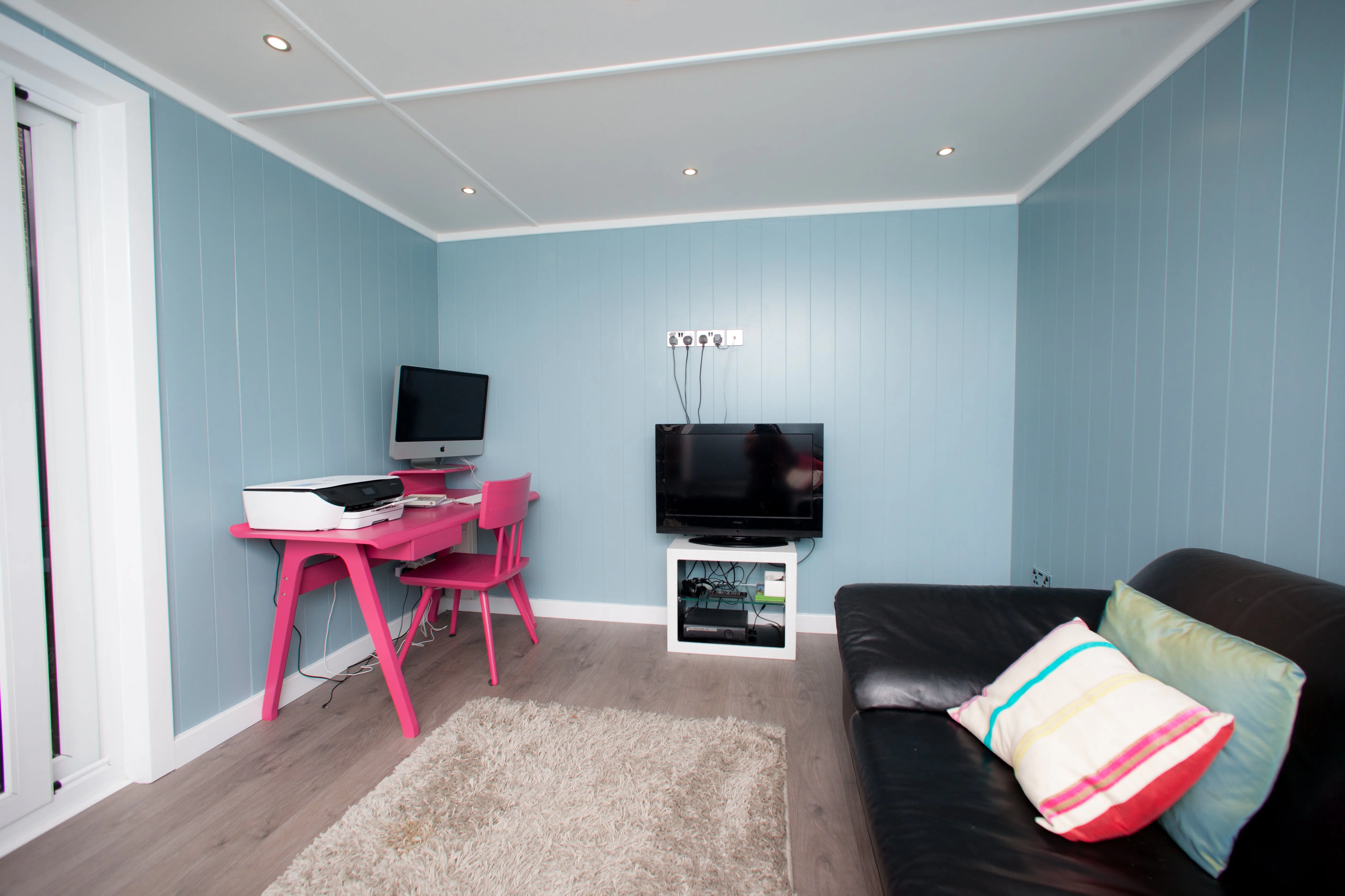 Cabin Master Inside View of summerhouse with blue walls and rug and office furnishings and sofa and tv 