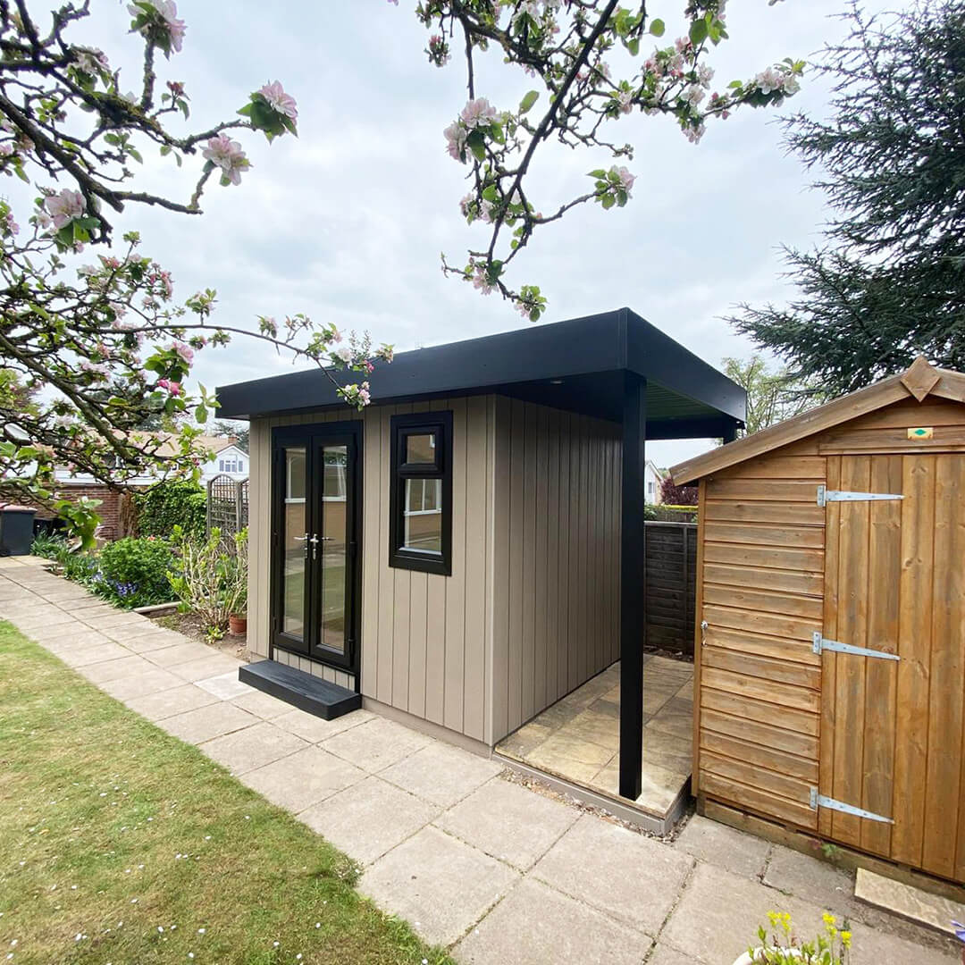 small marley garden building with veranda on patio pathway with small wooden shed next to it