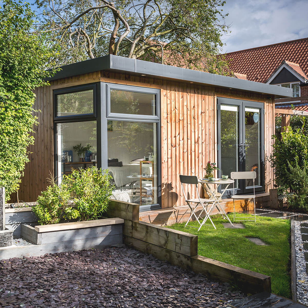redwood garden beauty room studio with large gravel area and small fence with lawn and table and chairs 