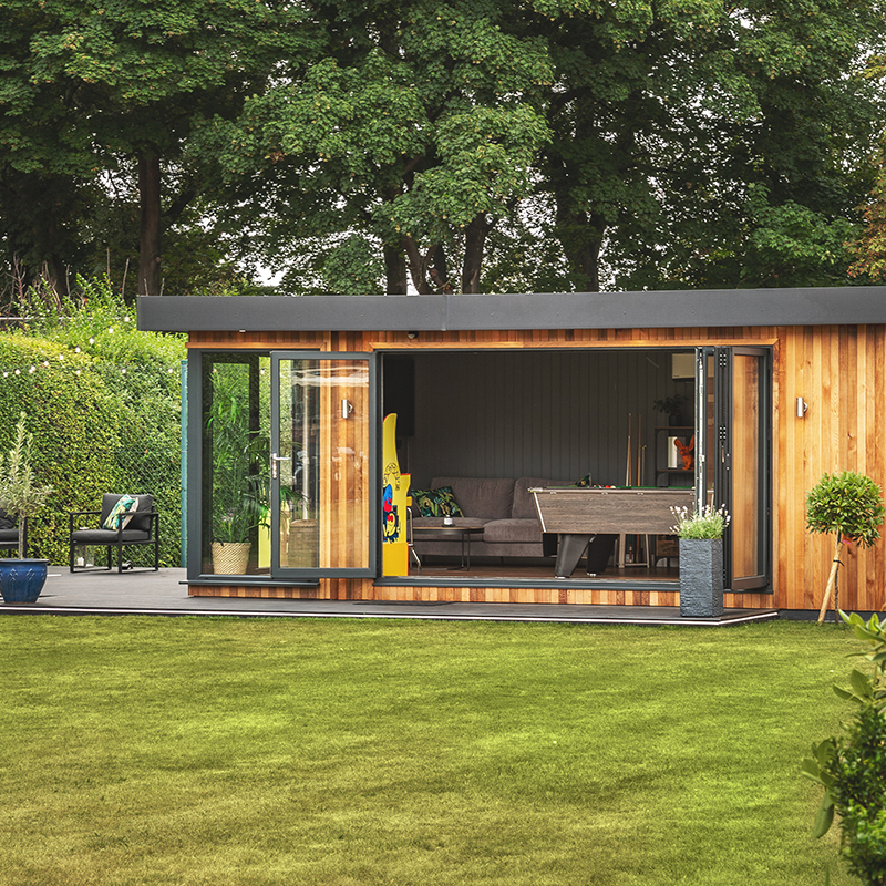 large cedar garden room with open bifold doors and large green lawn area with timber step