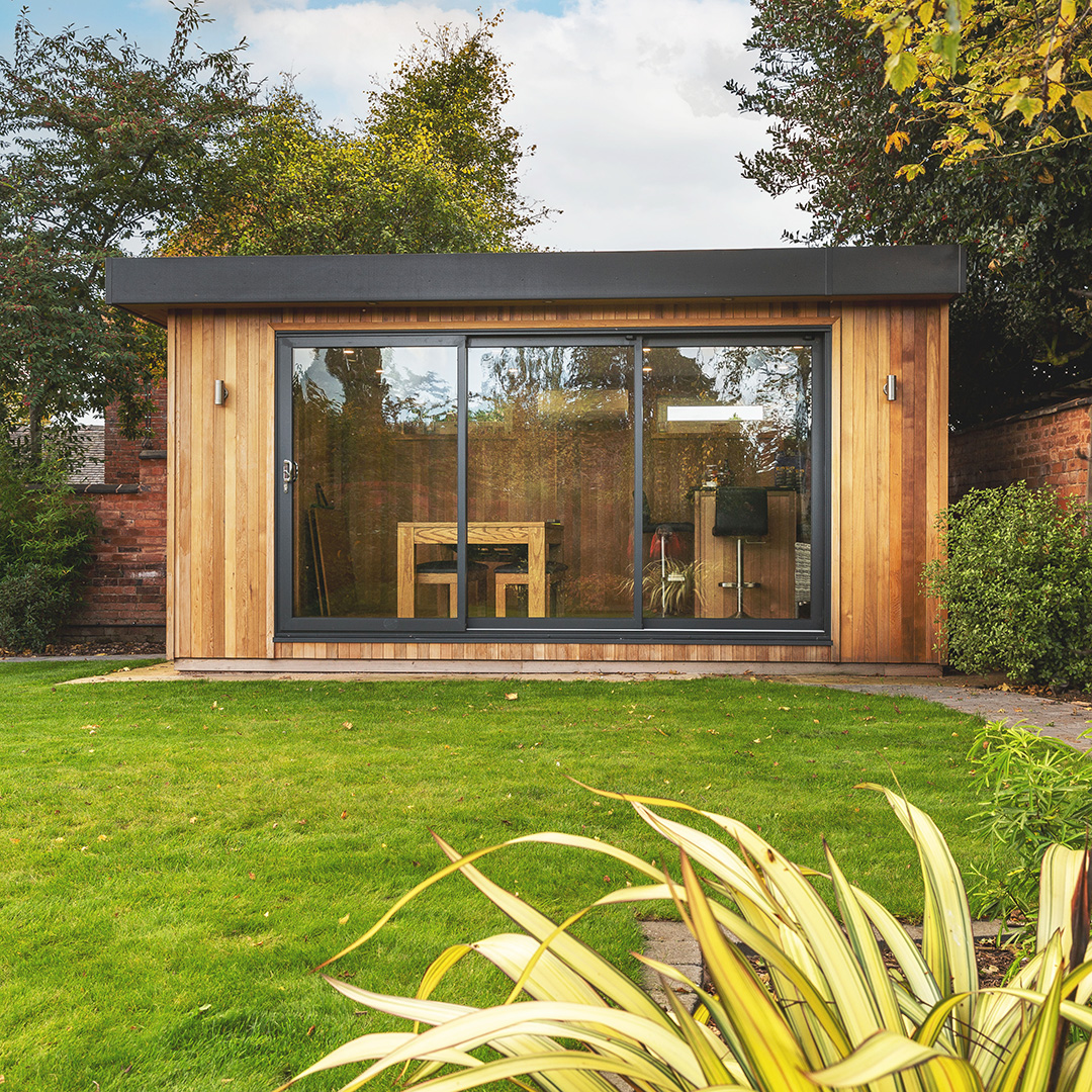 a timber garden building man cave with a patio walkway and large lawn area and large glass doors