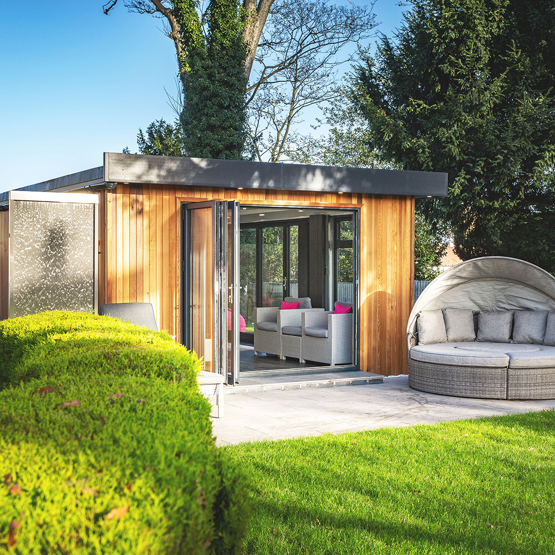 small garden summerhouse with open french doors and couch with furniture and decking