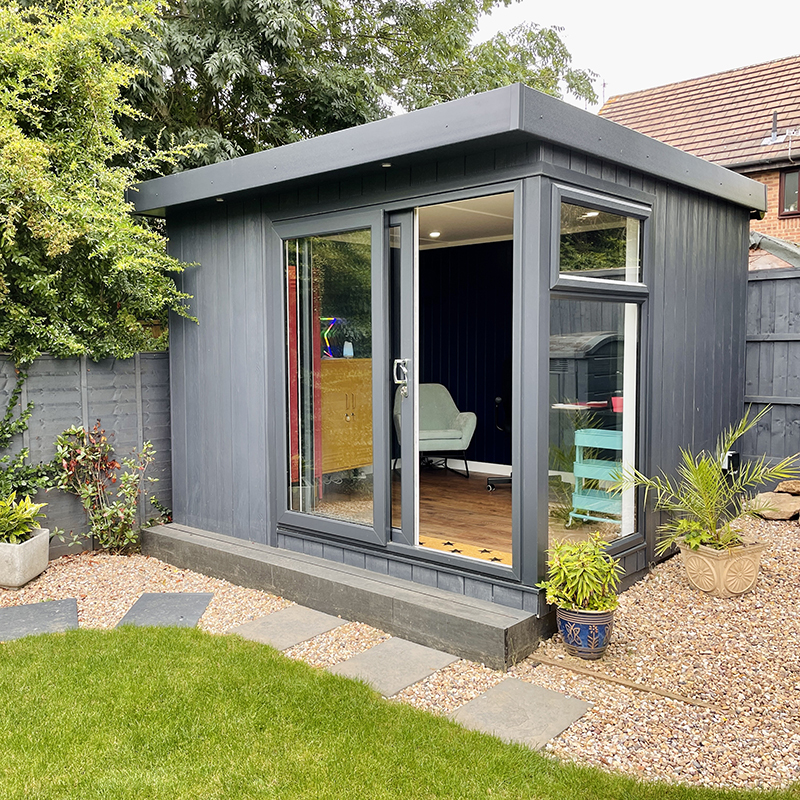 Small Home Office Building Micro Office in garden with potted plants and gravel pathway