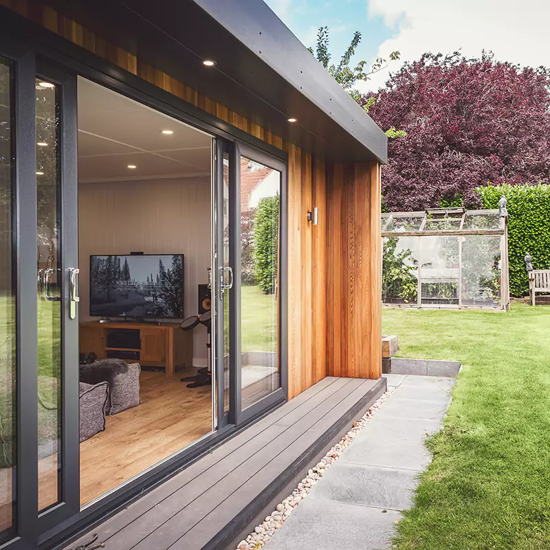 Cabin Master Cedar Garden Building with sliding doors and view of television with composite decking and patio and green grass garden area
