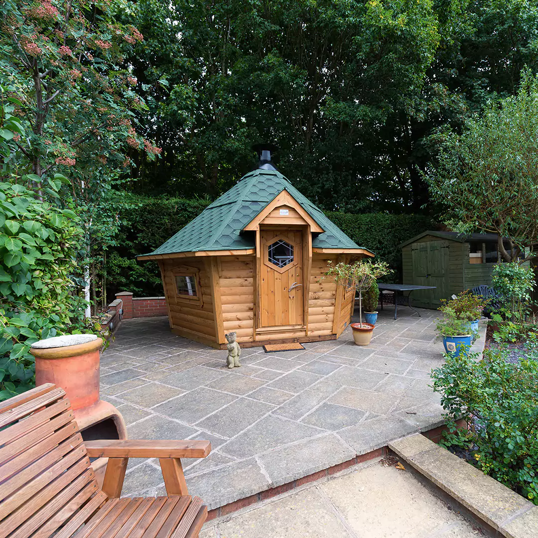 Hobbit house grill hut on stoney decked area with trees surrounding