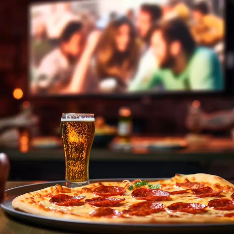 interior of a garden home cinema room with pizza & beer in foreground, cinema screen in background