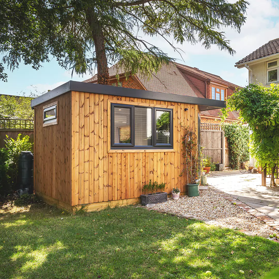 Small corner room garden office in redwood, with black doors and windows