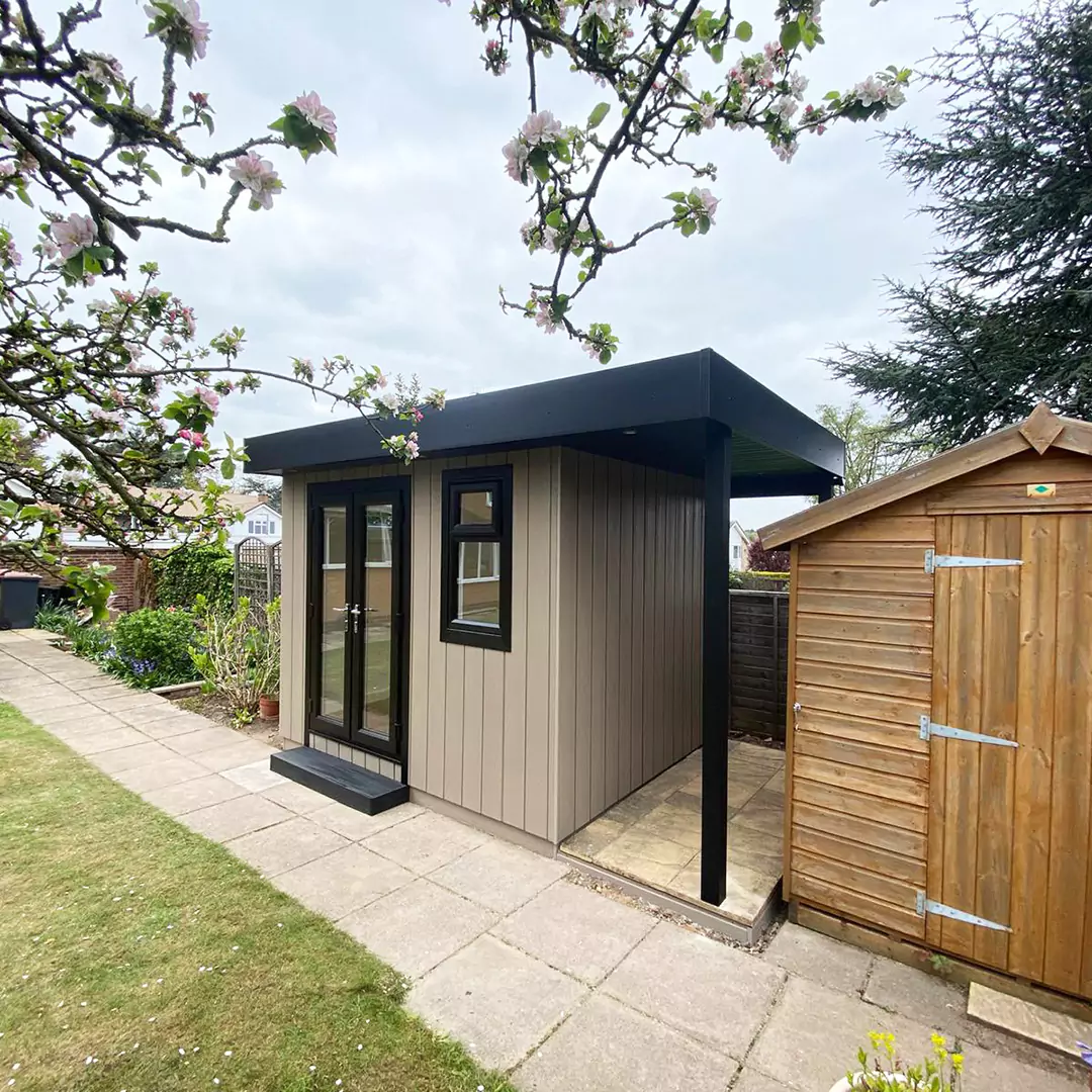 small Veranda Garden Building with patio area on the side and wooden shed and green grass lawn area 