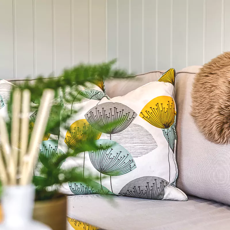 comfy sofa, reed diffuser & plant inside a garden room