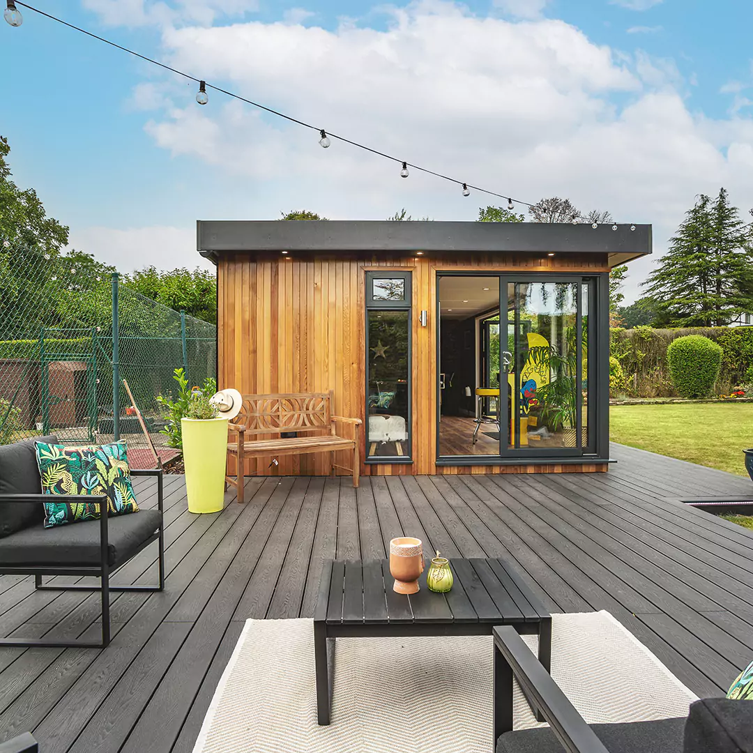 large garden building with man cave and potted plant and wooden decking 