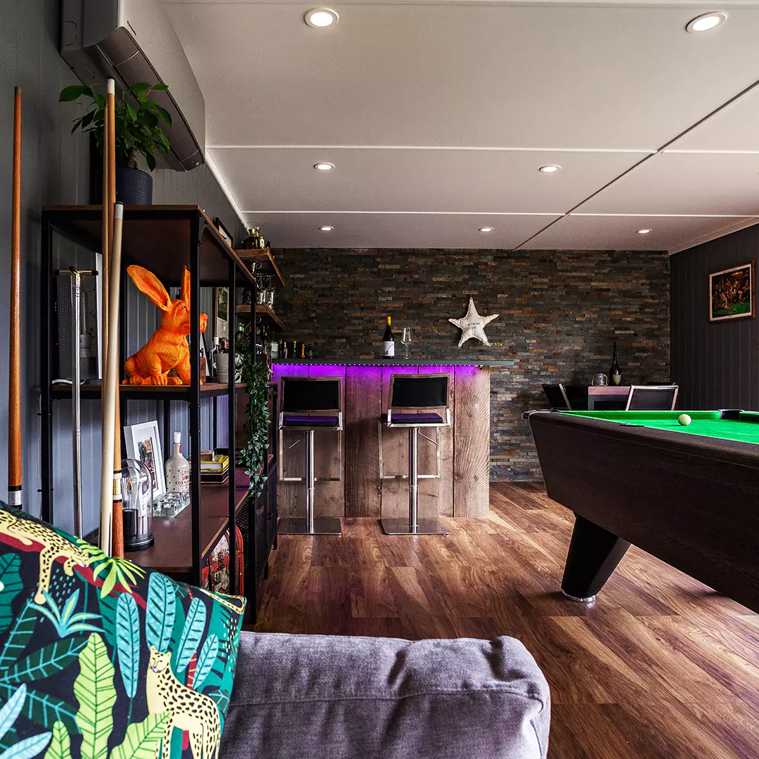 Inside a garden bar with pool table and shelving unit with brightly coloured accessories