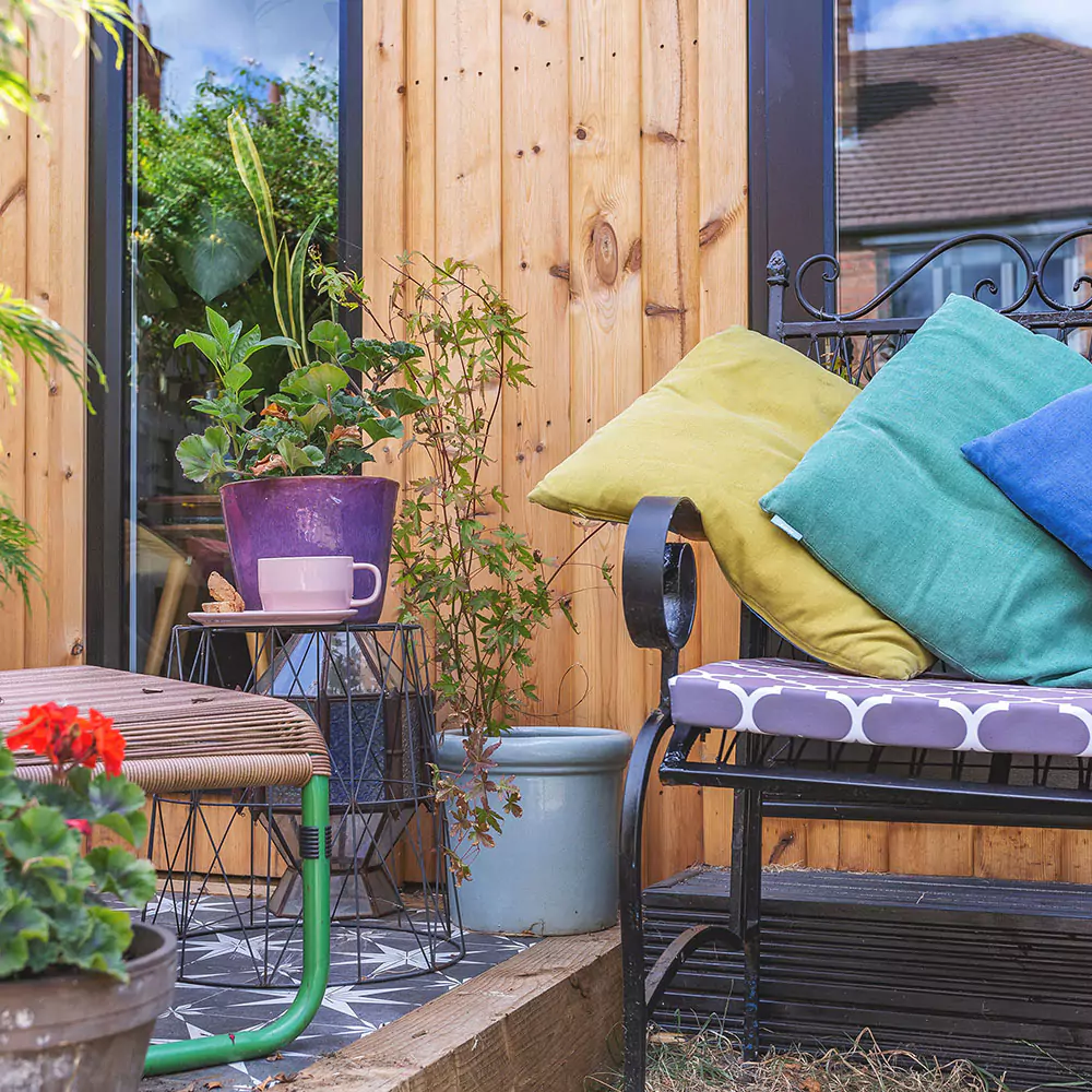 Close up of a redwood garden office with bright cushions on sofa outside