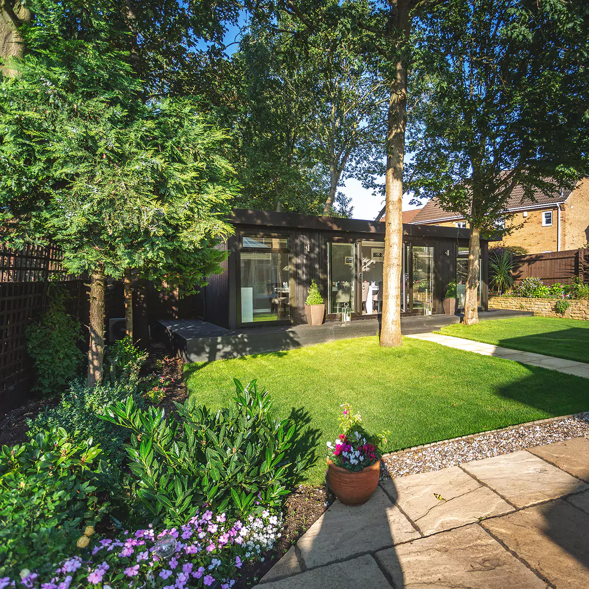 Cabin master dining room and oak tree in front of building with large green lawn area and patio and potted flowers