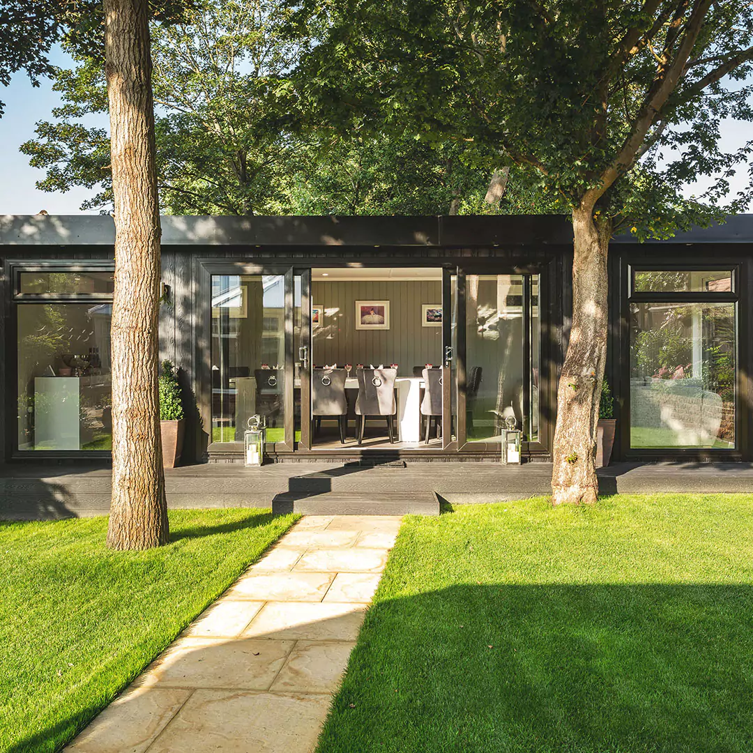 Marley Garden Dining Room Cabin Master Timber Building with large oak tree in front of open sliding doors and potted plant at the side 