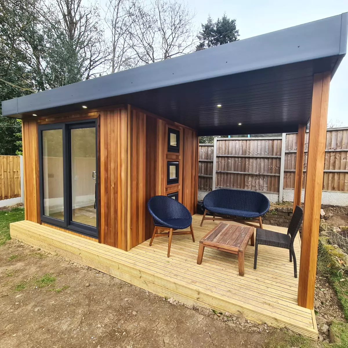 Cedar Garden Room with veranda in grassy lawn with large black doors and windows