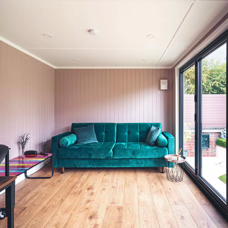 external view of garden room with open bi-fold doors and partition doors and large green velvet sofa and office furnishings