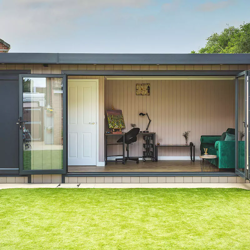 external view of garden room with open bi-fold doors and partition doors and large green velvet sofa and office furnishings
