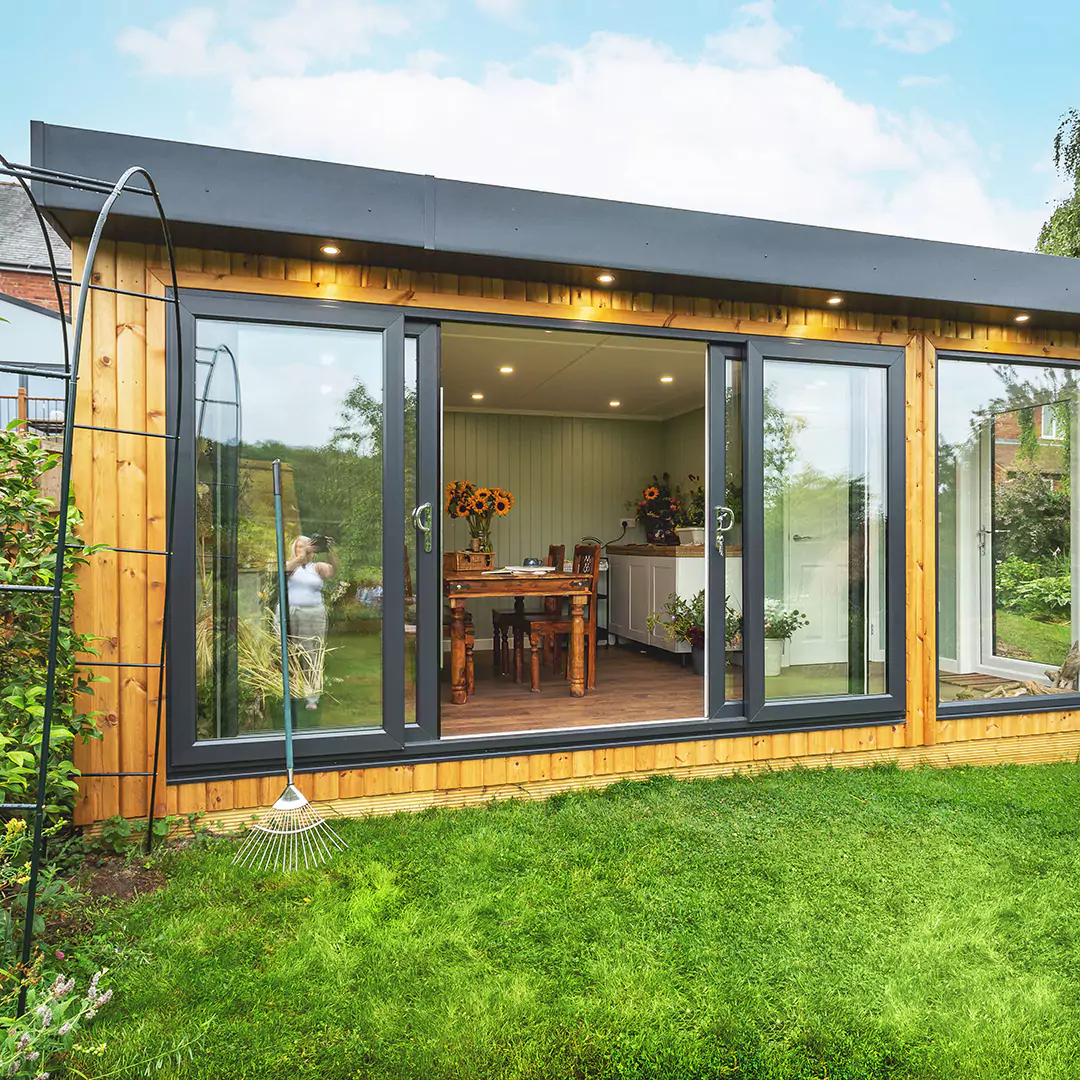 garden room with sunflowers in a vase on top of table with view of lawn and hedges