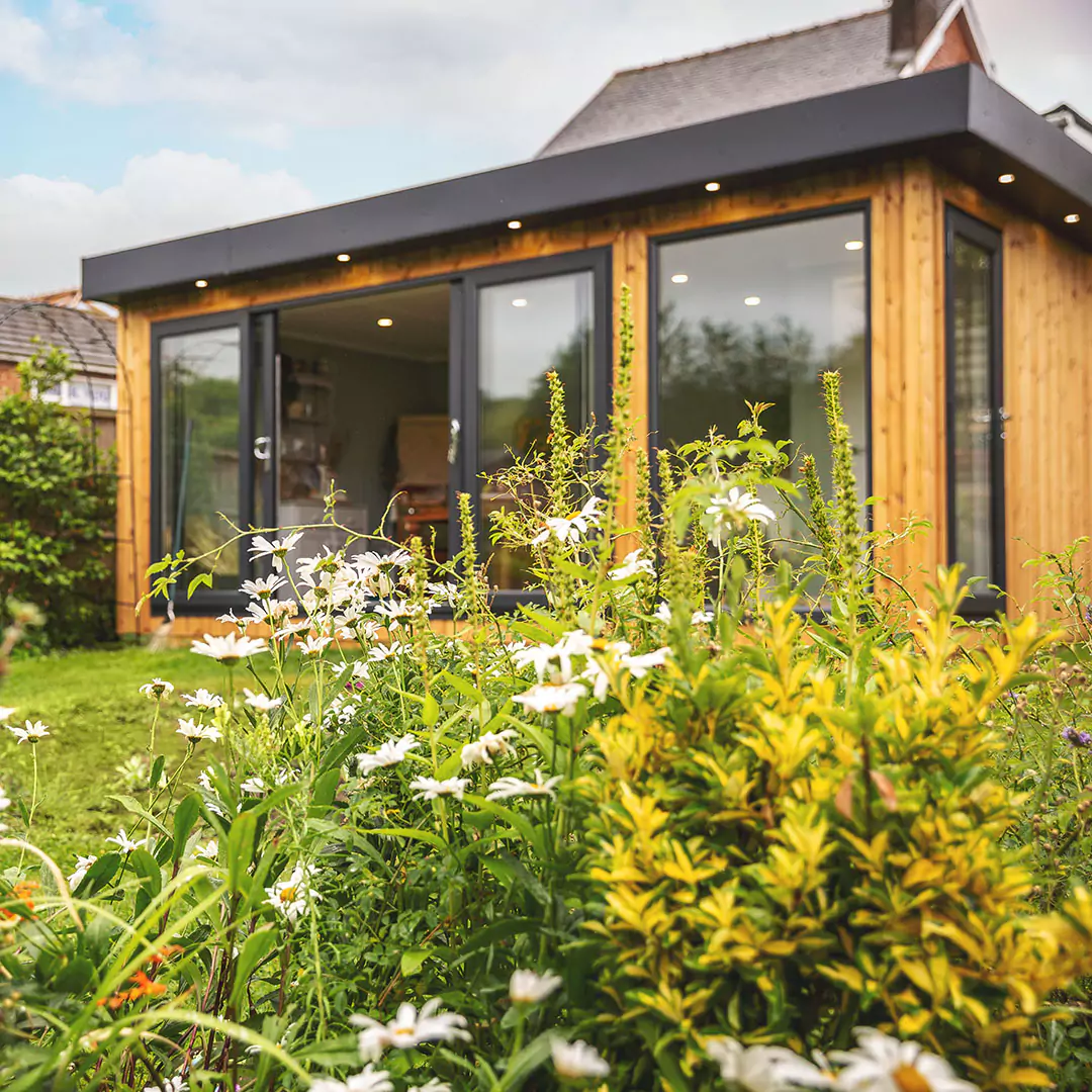 garden room floristry studio with green hedges surrounding it 