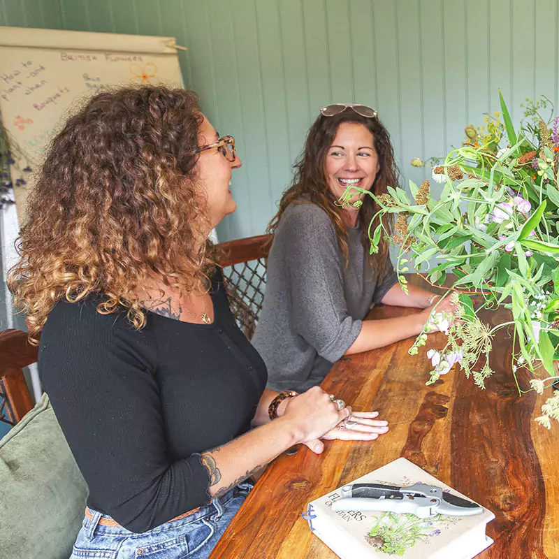 women sat down at table enjoying a floristry workshop