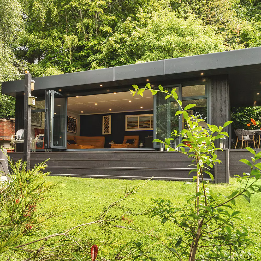  black marley board garden building with open bifold doors and garden furniture outside