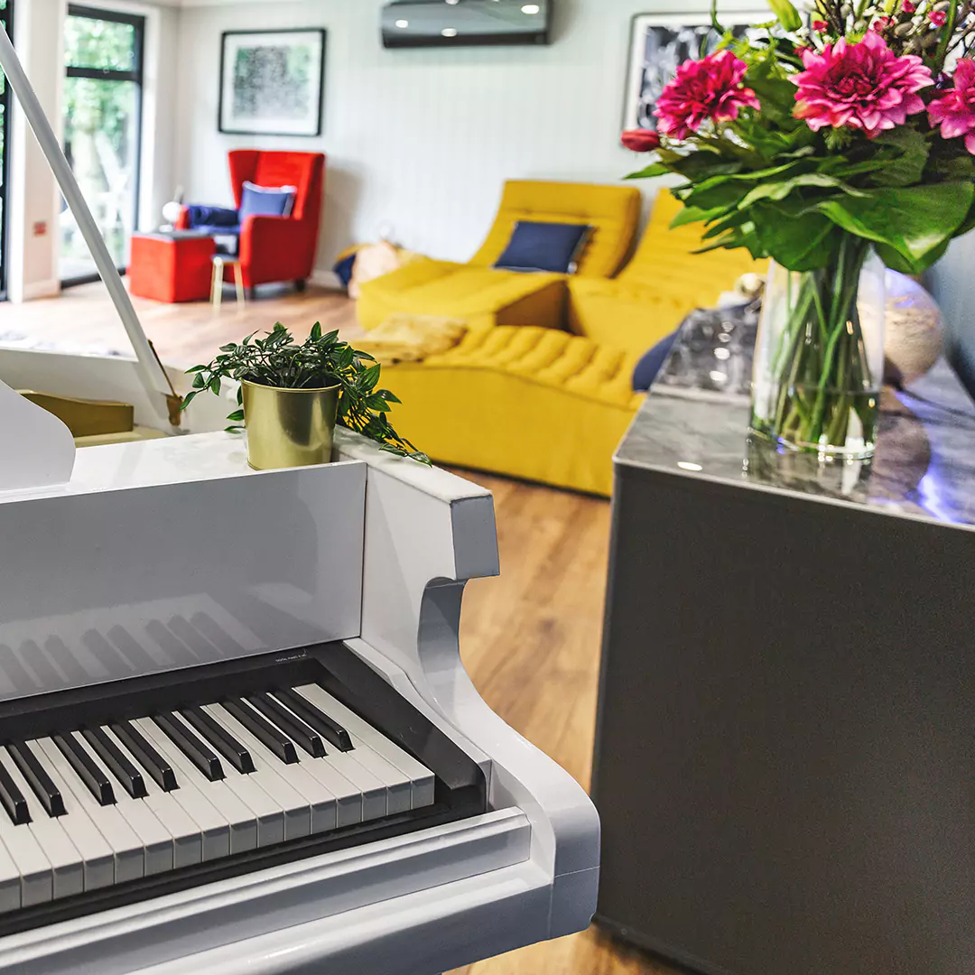 a piano in a garden room with veranda with a vase of flowers