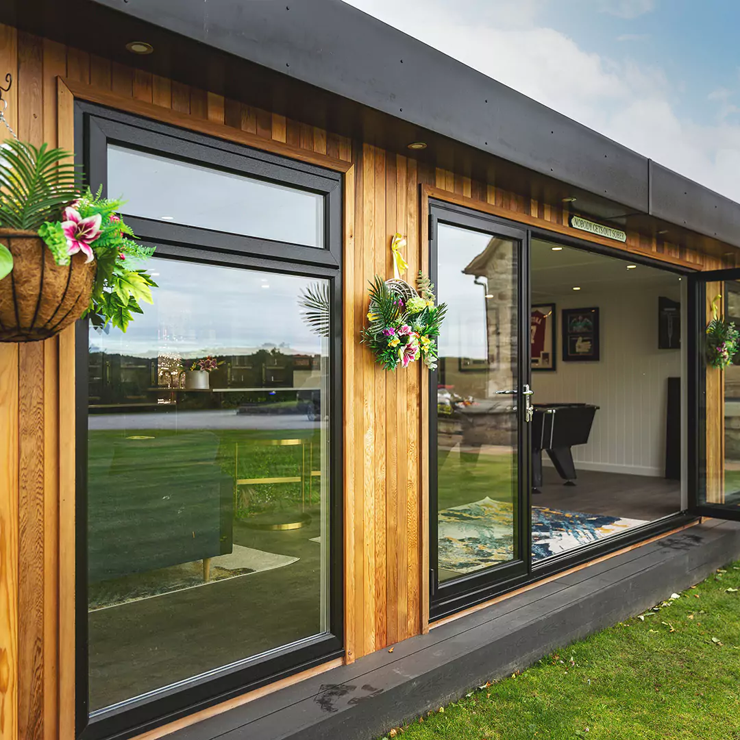 Outdoor image of hanging plants and cedar building and bifold doors