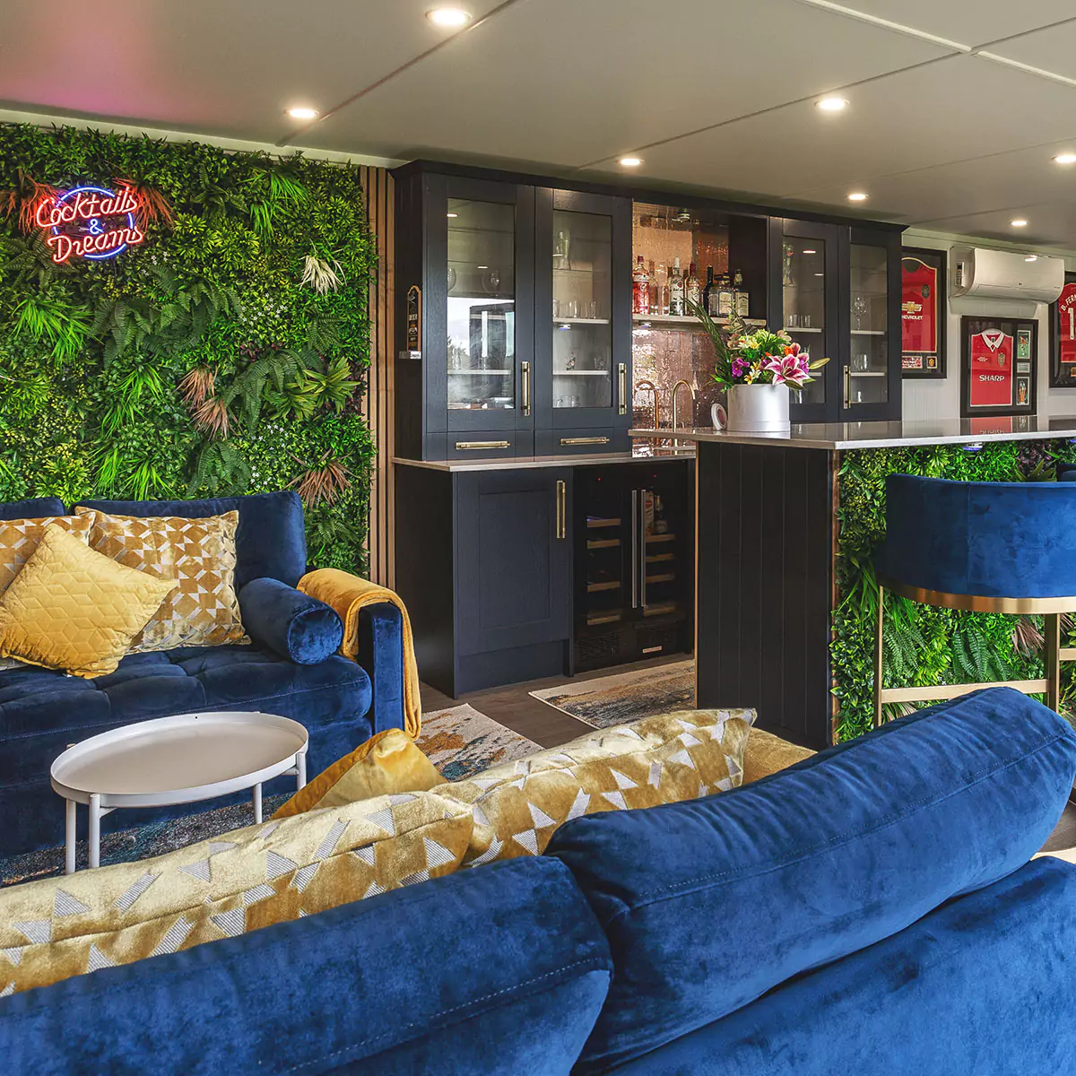 garden bar with velvet blue sofas and indoor plant wall with neon sign