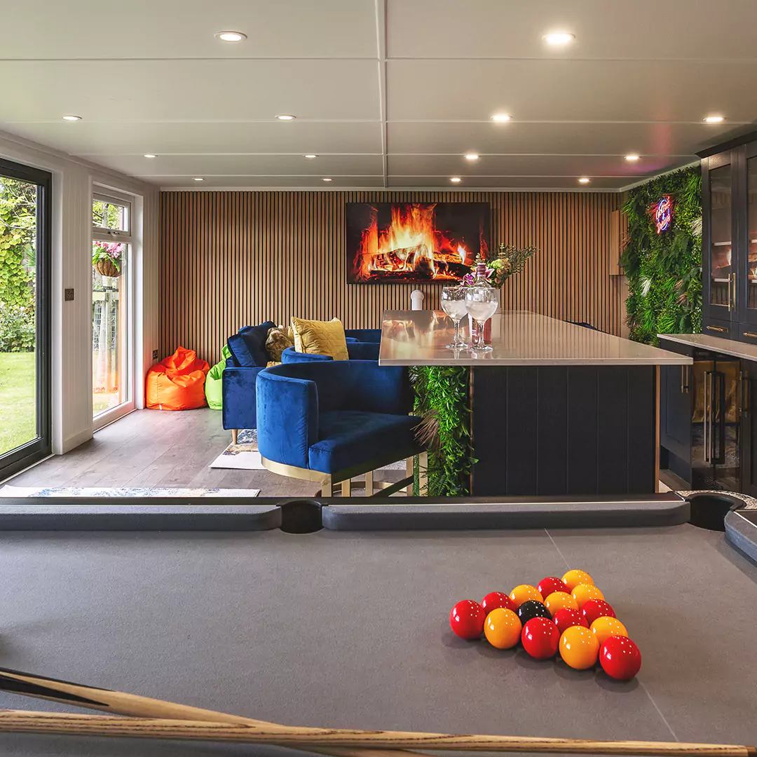 Interior garden bar ideas with slatted panel wall, pool table, bright furnishings, faux foliage wall and neon sign