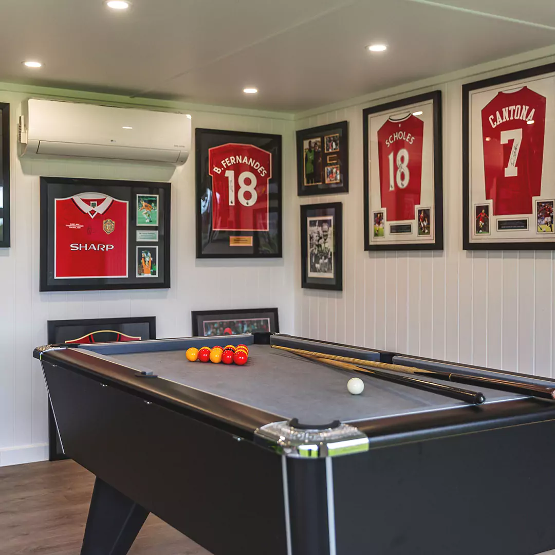 Inside a garden bar with pool table and framed Manchester United shirts and air con unit