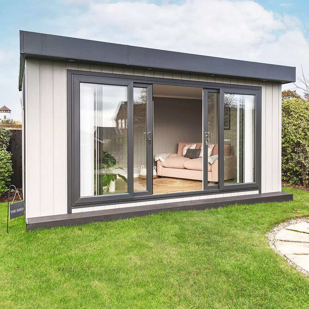 Zero maintenance garden office with bi-fold doors in neat garden with pond and pump