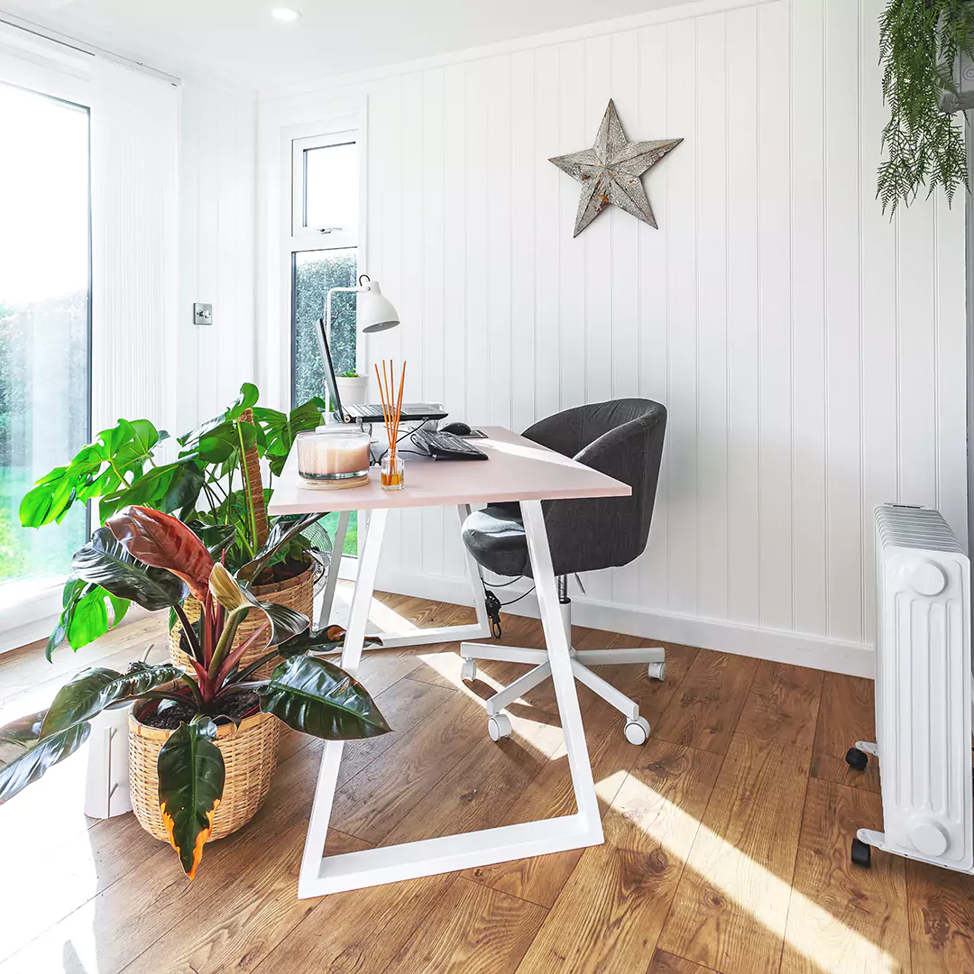 garden office space with large white desk and chair and large indoor house plants with wall hanging 